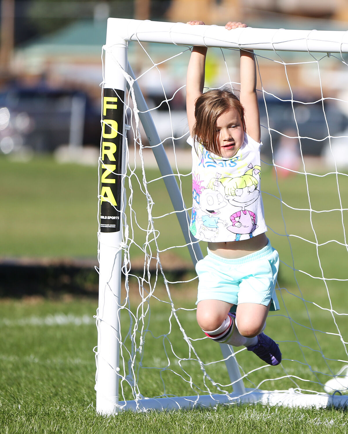 Alivia Schroth, 4, hangs on the goal while she waits for the ball